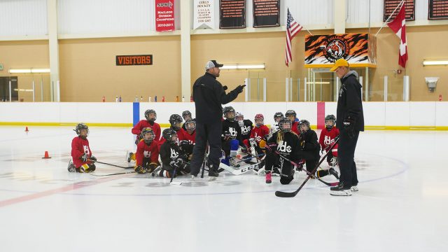 David Cullen and instructors talk to young students on the ice